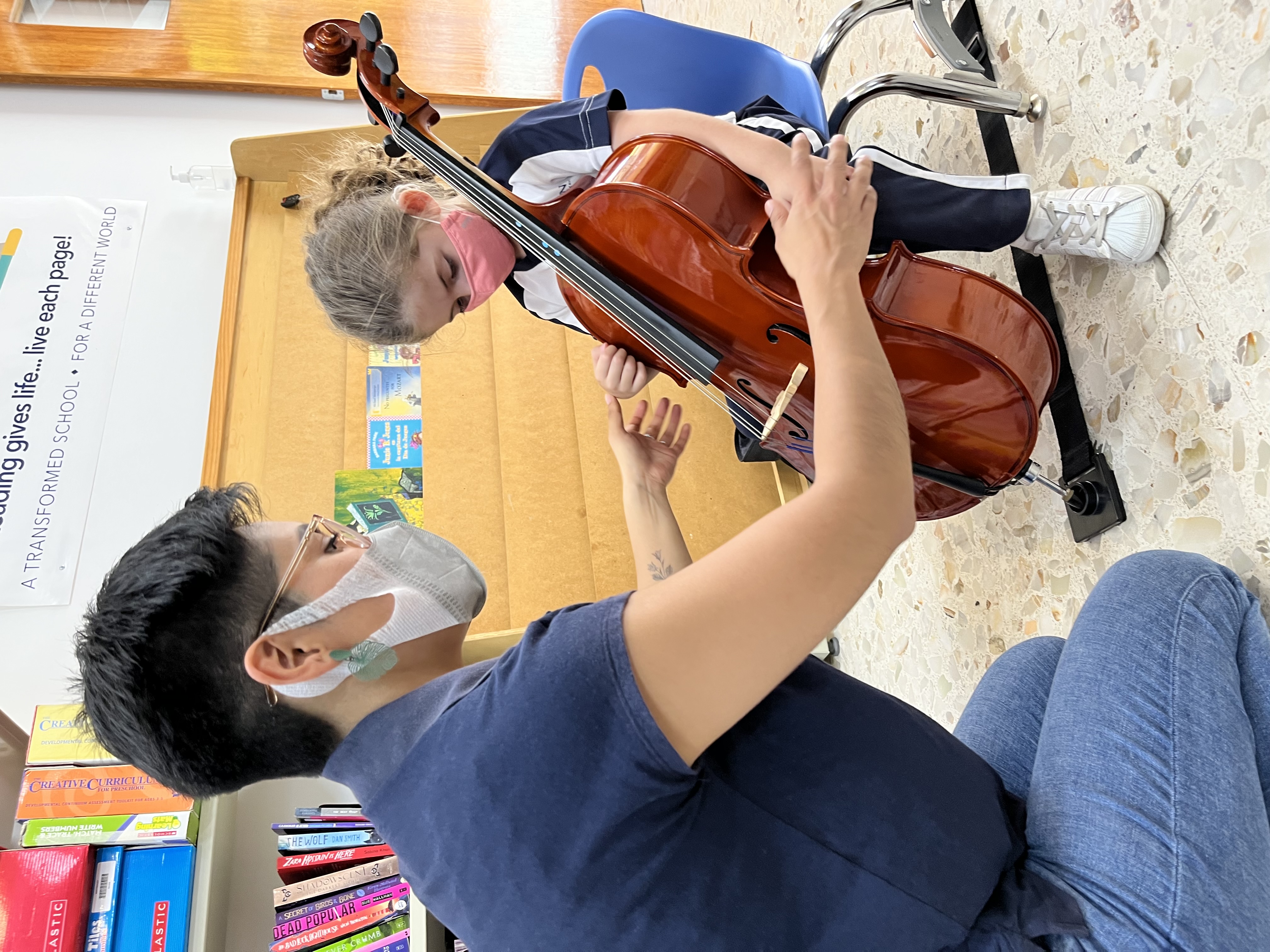 Foto de maestra de chelo ayudando a su alumna de 5 años.